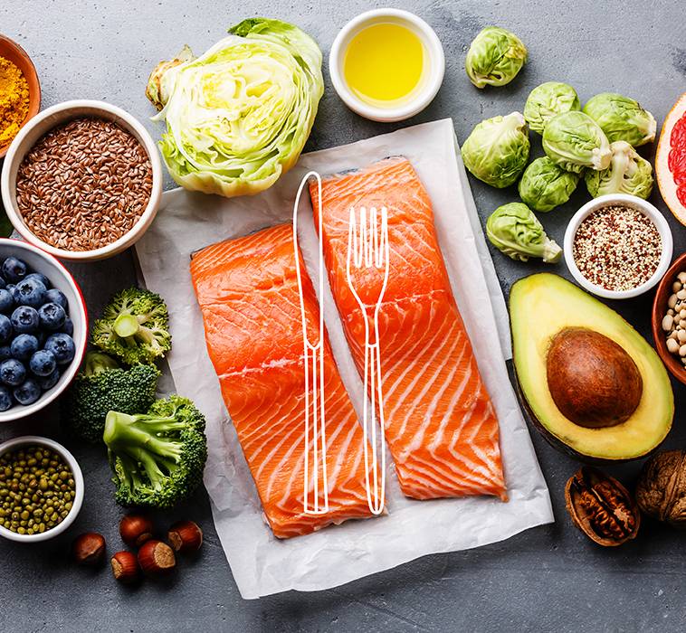 A granite tabletop displaying ingredients for a dish, including raw salmon fillets, fresh vegetables